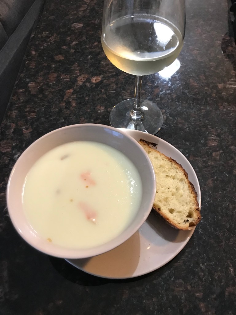 potato soup and slice on bread on plate next to wine glass
