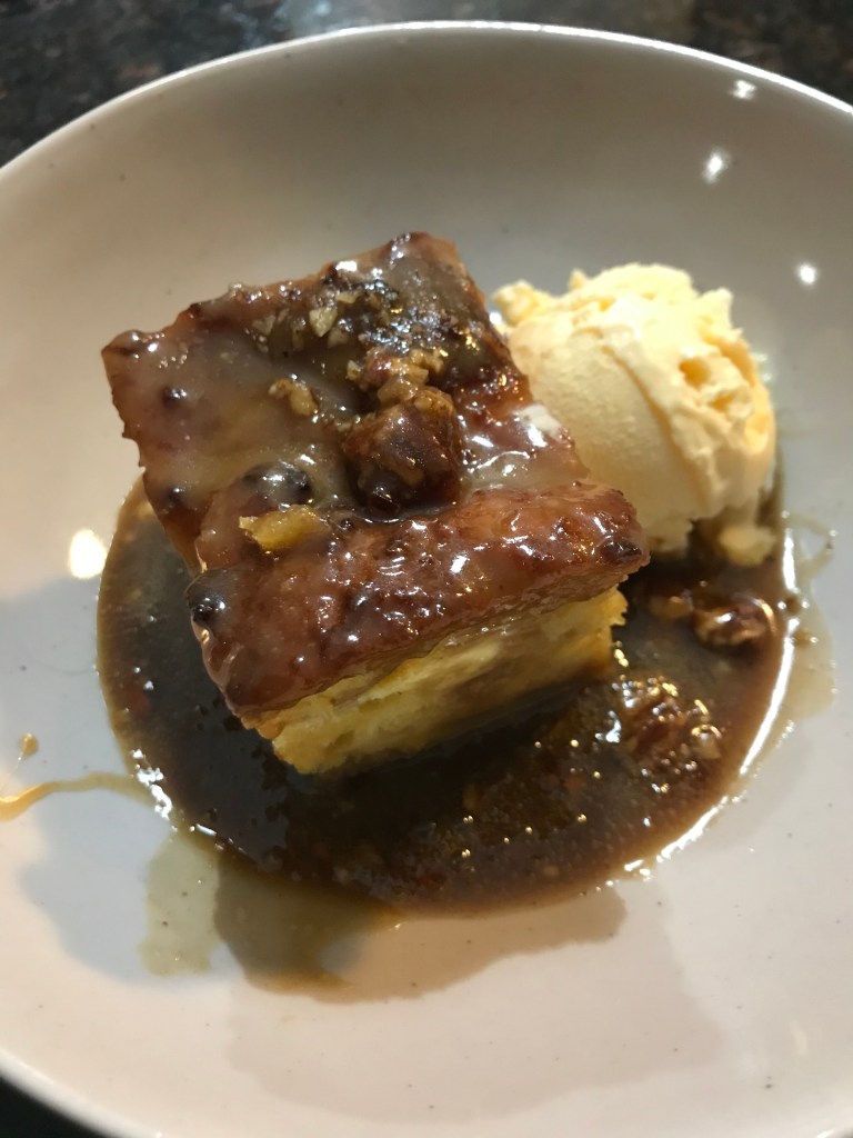bread pudding in caramel sauce next to ice cream