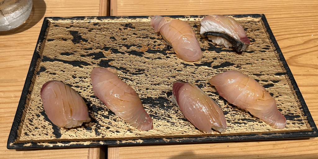 Six pieces of amberjack and Spanish mackerel sushi on a platter