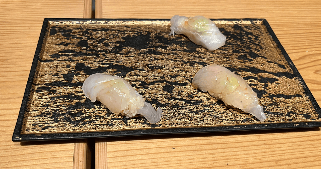 Three pieces of snapper sushi on a rectangular platter