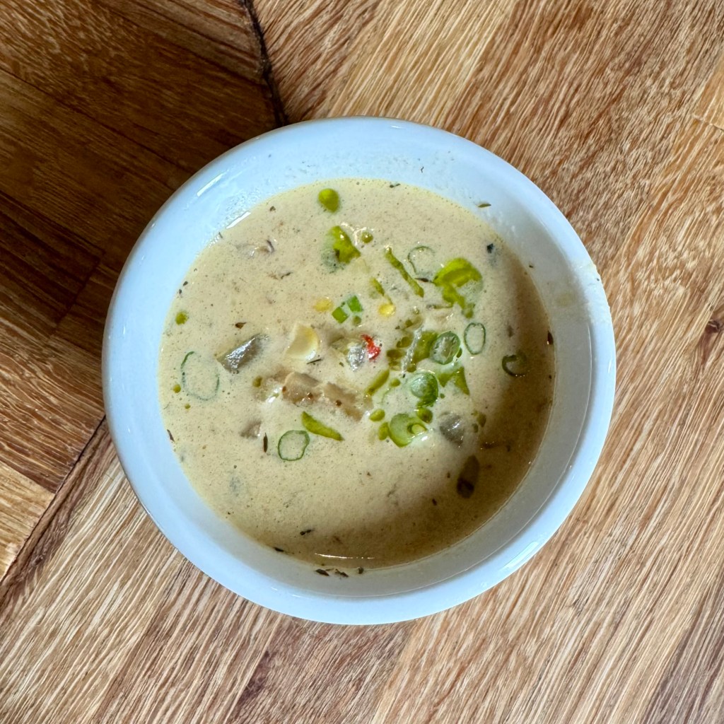 A bowl of corn chowder with scallions on top